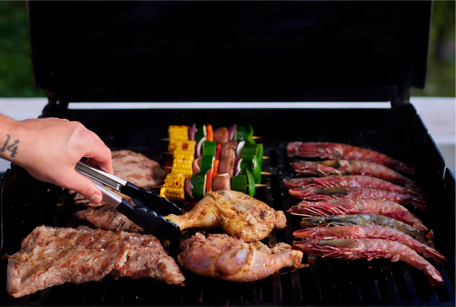 A selection of seafood, meats, and vegetables on the barbecue grill.