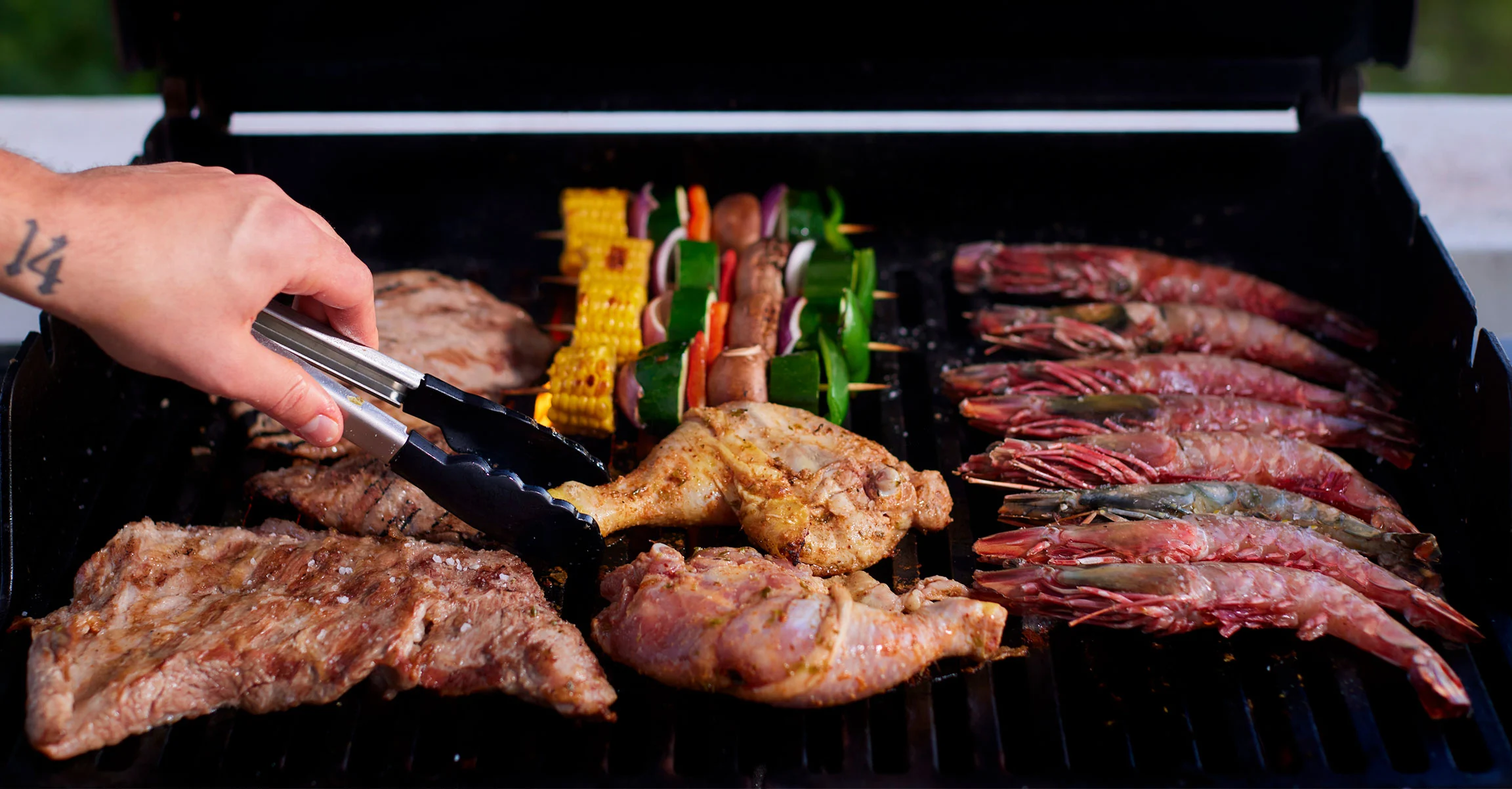 A selection of seafood, meats, and vegetables on the barbecue